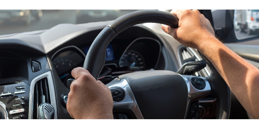 Man's arms on a steering wheel