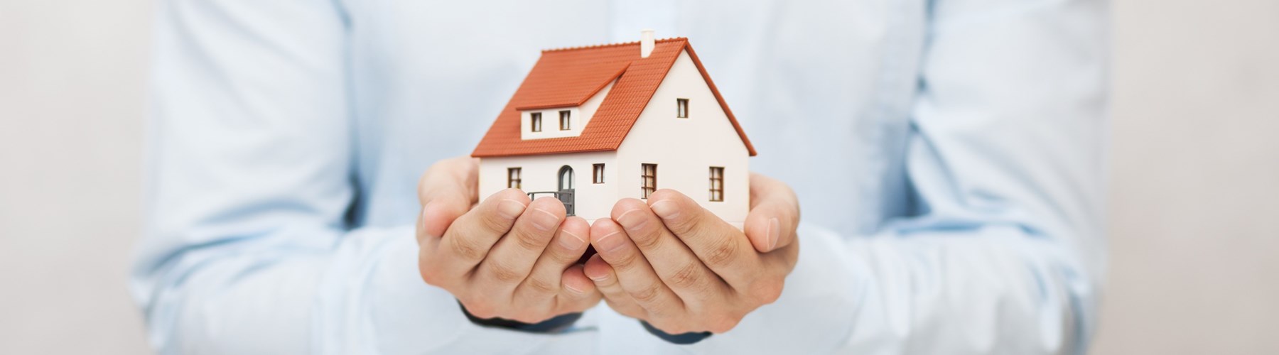 Man's hands holding model house