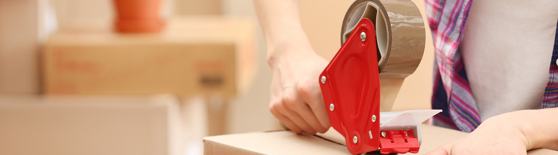 Cardboard box being taped using sellotape dispenser 