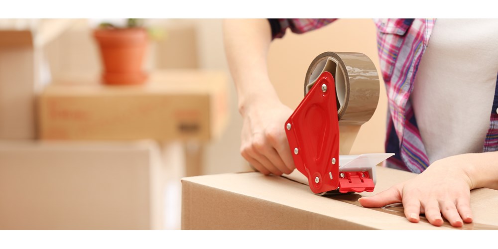 Cardboard box being taped using sellotape dispenser 