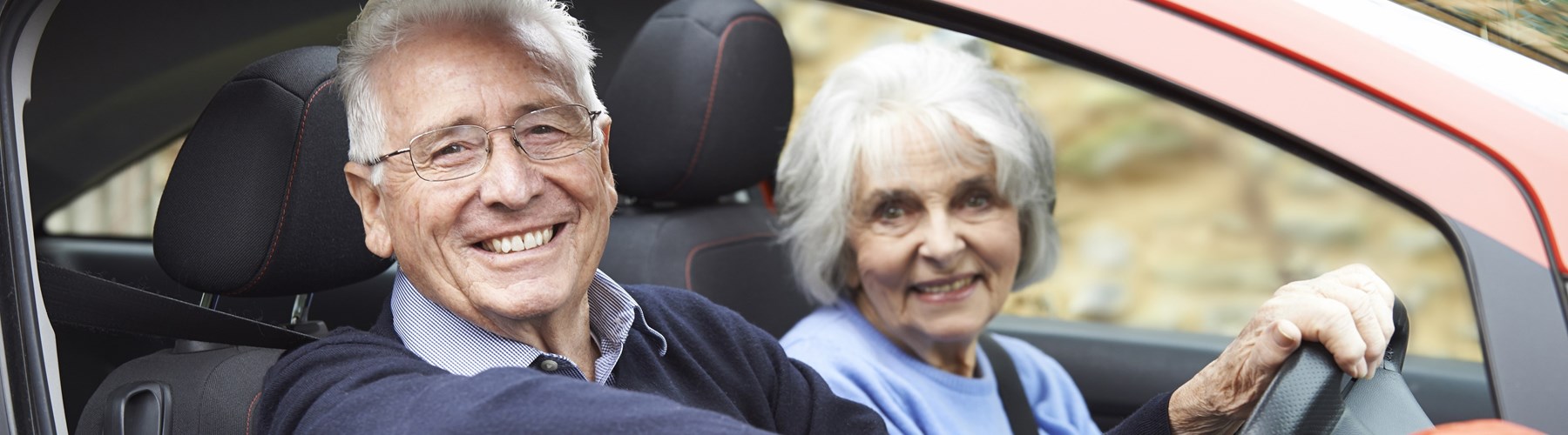 Older couple in an orange car