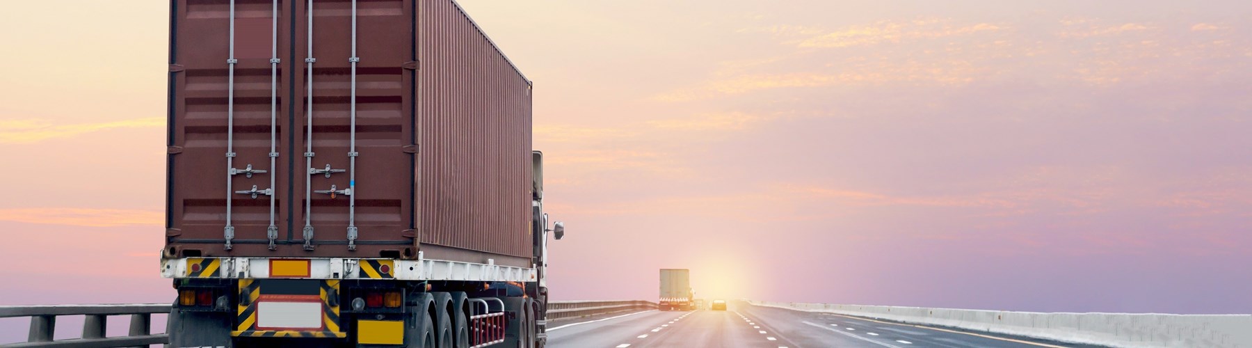 Red import truck travelling on the right side of the road