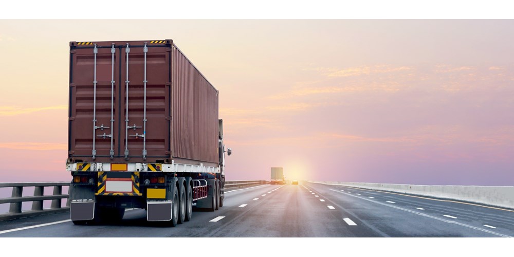 Red import truck travelling on the right side of the road