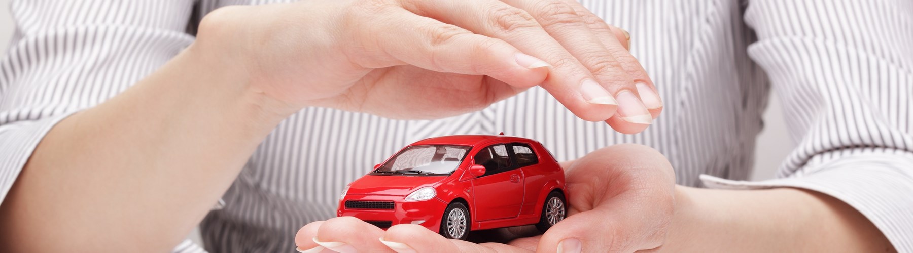 Red toy car held and covered by a woman's hands