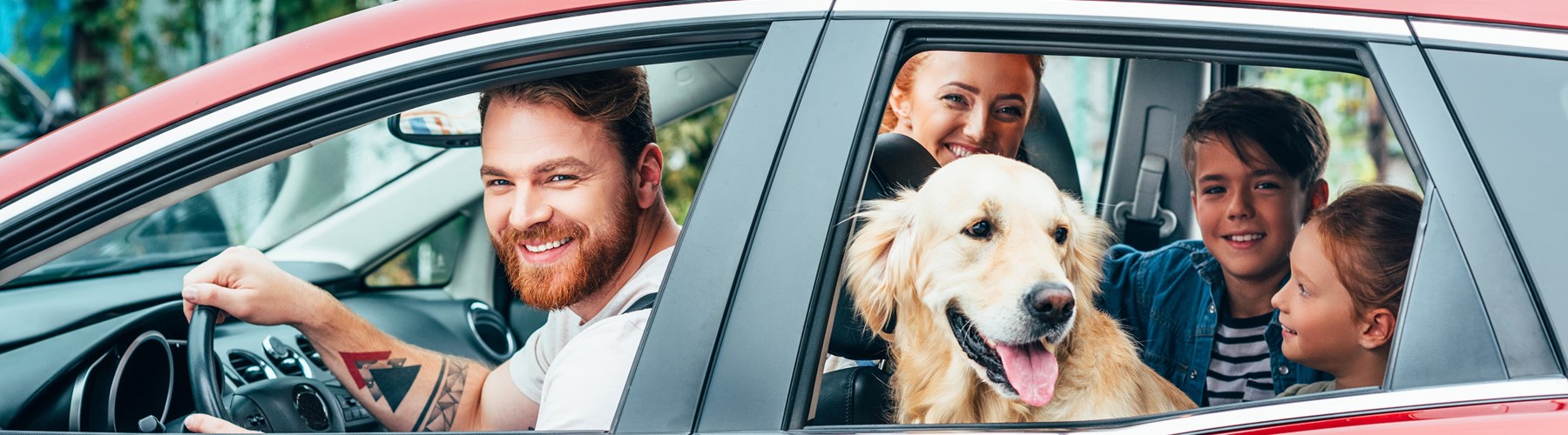 family and dog in red car 