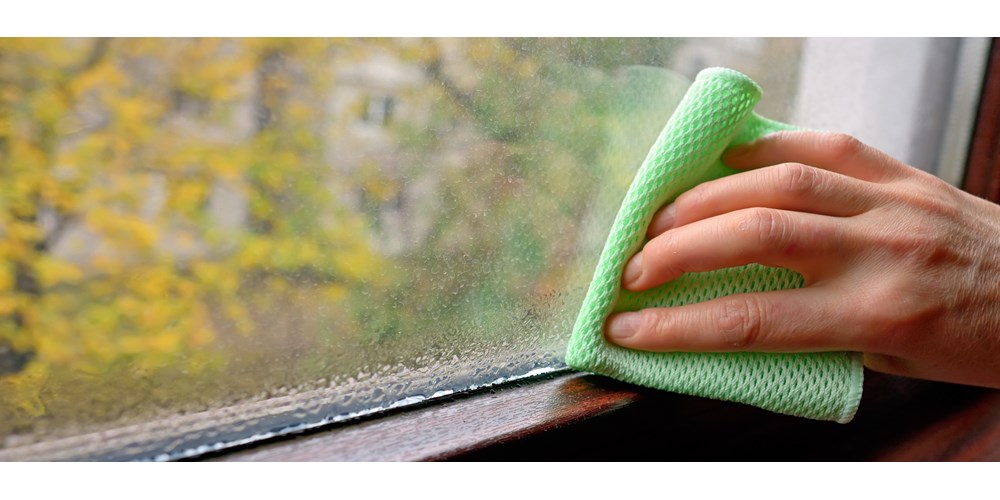 Man wiping condensation off windows