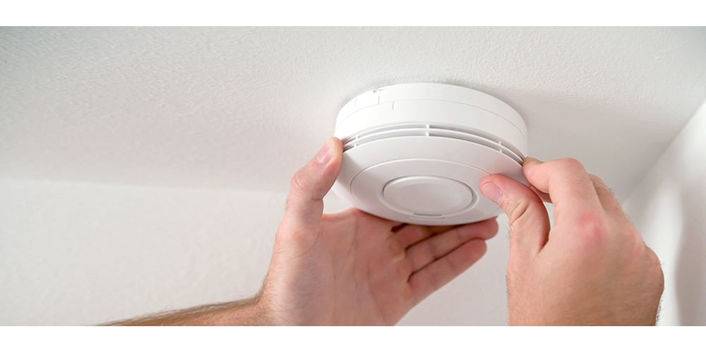 Man testing a smoke alarm in home