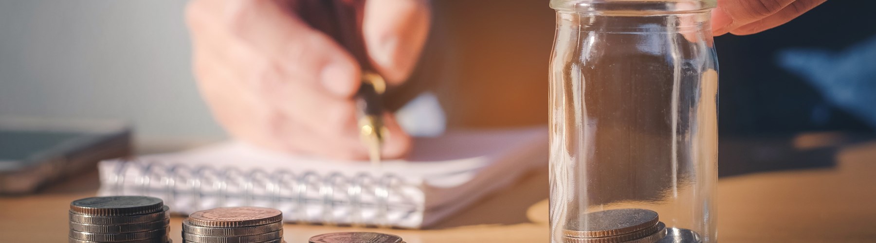 Man dropping coins into a saving jar