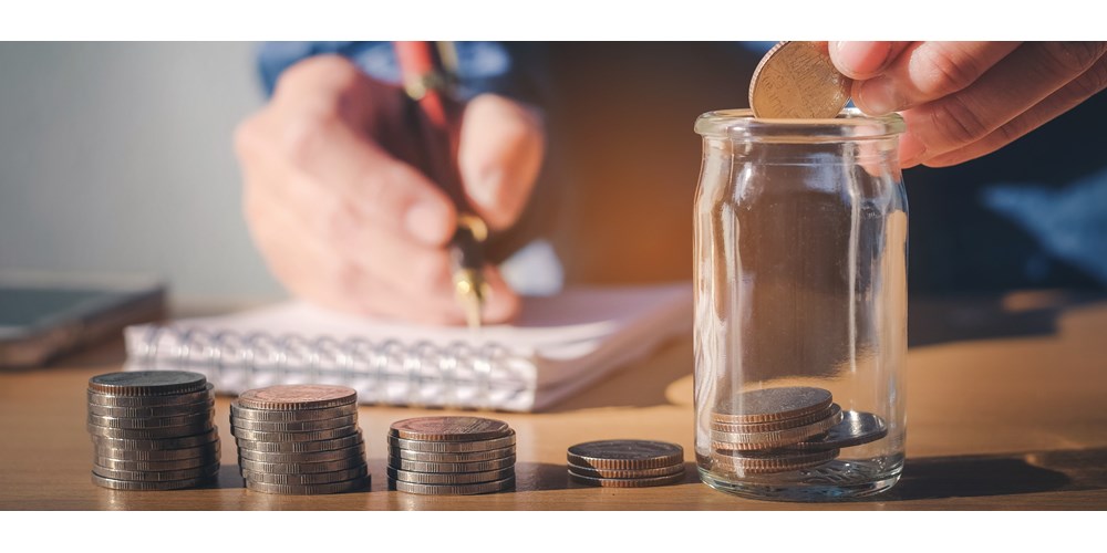 Man dropping coins into a saving jar