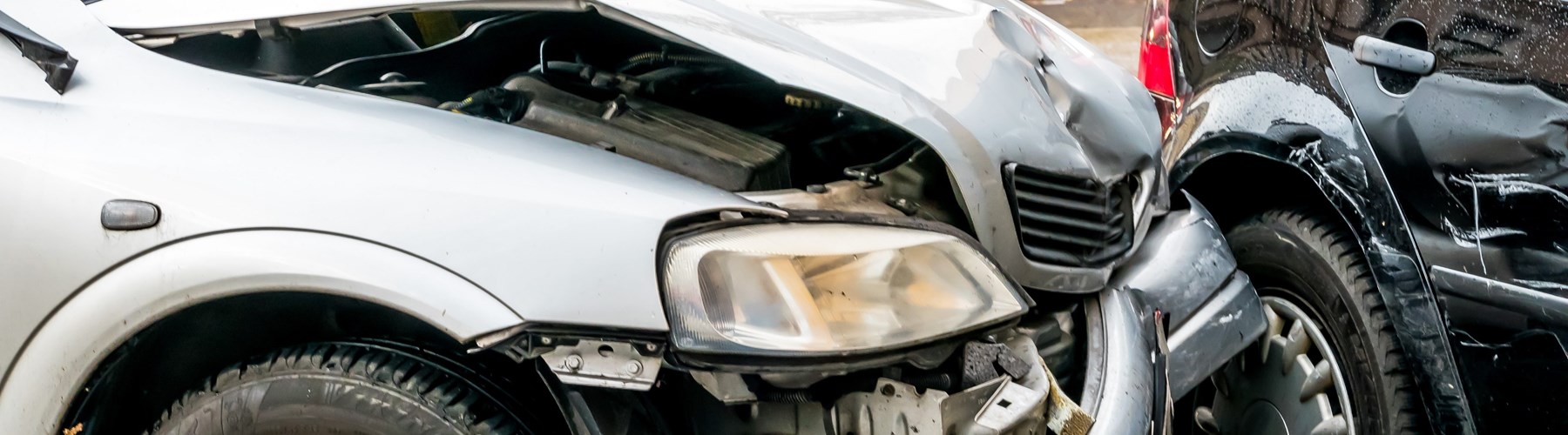 Silver car with frontal damage after crash