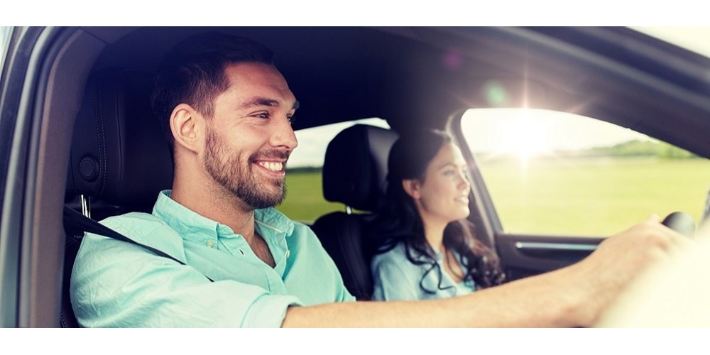 Smiley man driving car with woman in the passenger seat