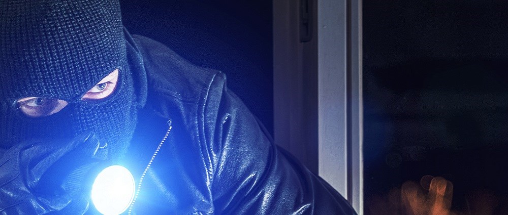 A burglar shining a torch at house