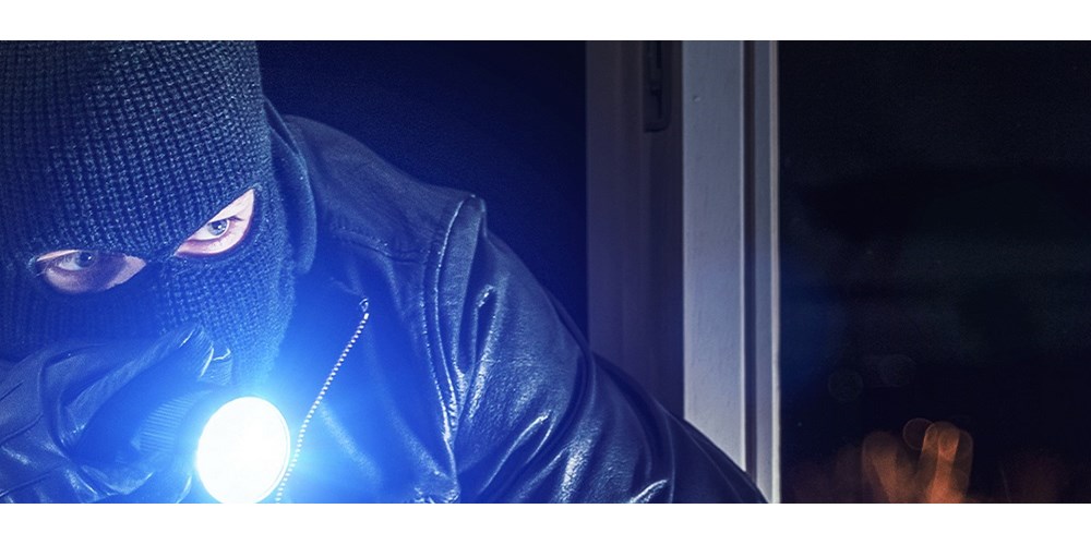 A burglar shining a torch at house