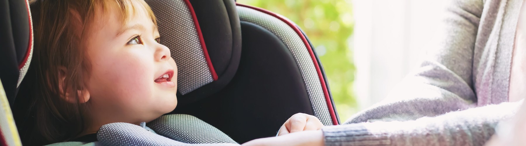 Toddler getting buckled up in her car sear