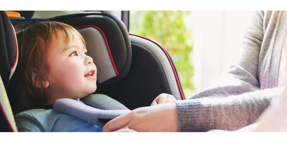 Toddler getting buckled up in her car sear