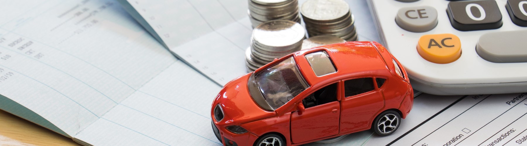 Red toy car with calculator and coins on top of documents
