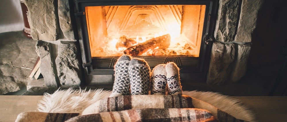Two pairs of feet with socks on by the fire