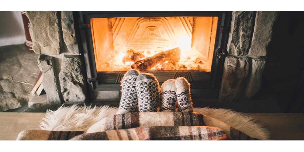 Two pairs of feet with socks on by the fire