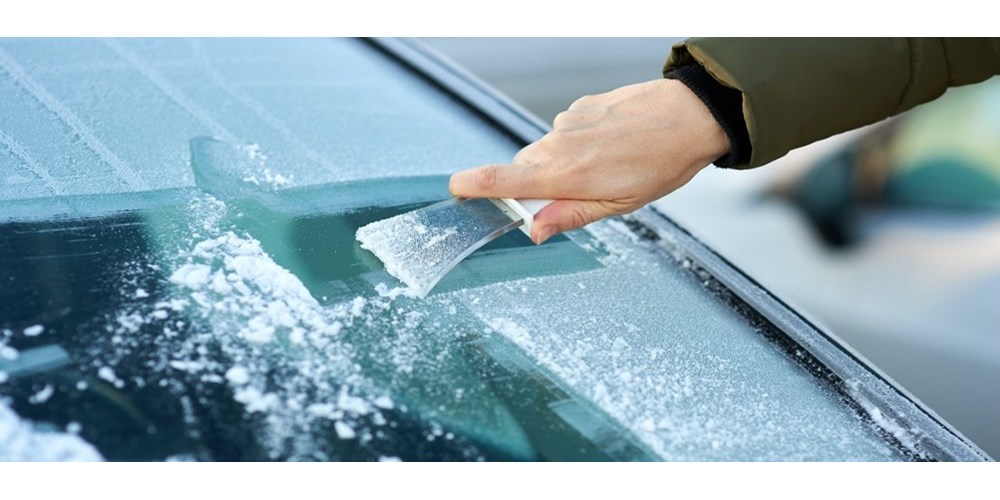 Person scraping ice of windscreen