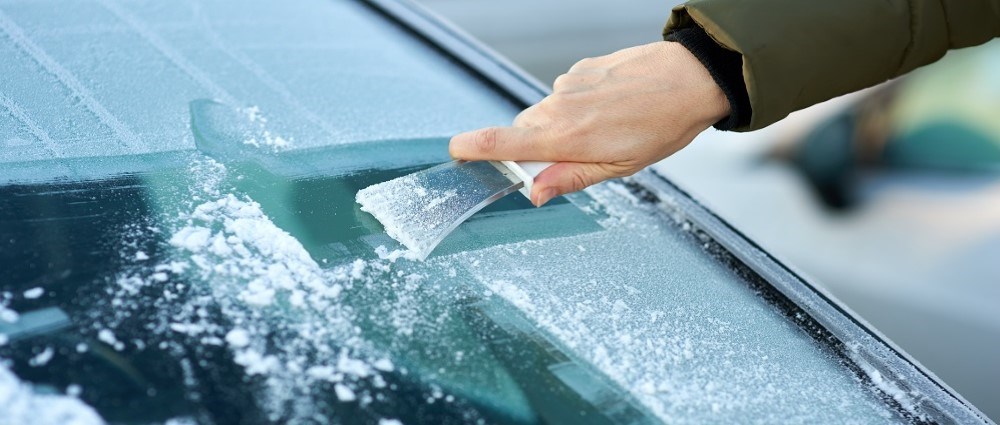 Person scraping ice of windscreen