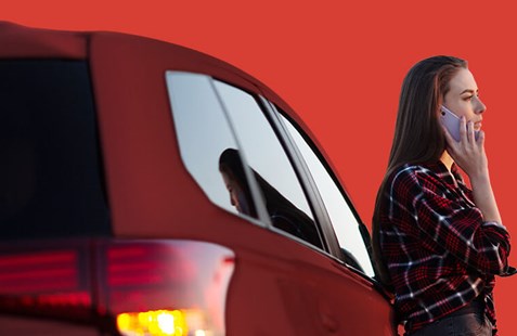woman on phone next to red car