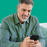 man on sofa with mobile on green background